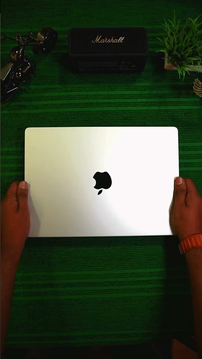A silver MacBook held at MacFreaks